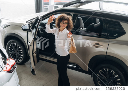 Walking out from vehicle, doors is opened. Pretty woman is in the car retail shop Walking out from vehicle, doors is opened. Pretty woman is in the car retail shop 136822020
