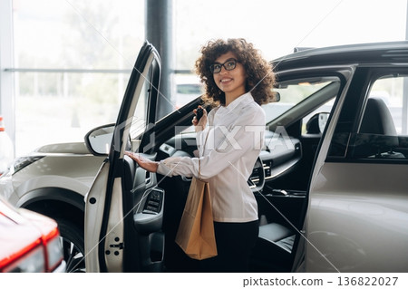 Walking out from vehicle, doors is opened. Pretty woman is in the car retail shop Walking out from vehicle, doors is opened. Pretty woman is in the car retail shop 136822027