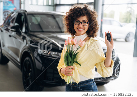 Present of flowers in hands. Pretty woman is in the car retail shop Present of flowers in hands. Pretty woman is in the car retail shop 136822123