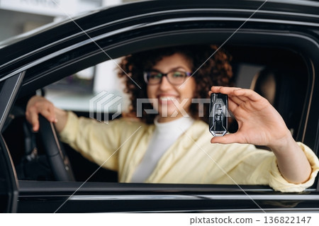 In glasses, with keys in hand. Happy woman is sitting in the car In glasses, with keys in hand. Happy woman is sitting in the car 136822147