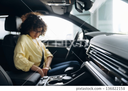 Fastens the seat belt. Happy woman is sitting in the car Fastens the seat belt. Happy woman is sitting in the car 136822158