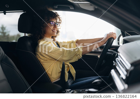 Driving, side view. Happy woman is sitting in the car Driving, side view. Happy woman is sitting in the car 136822164
