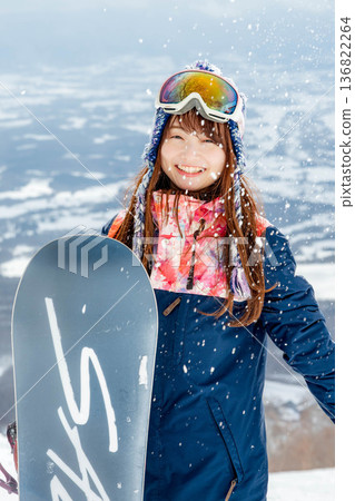 Young woman enjoying snowboarding at the top of the slope 136822264
