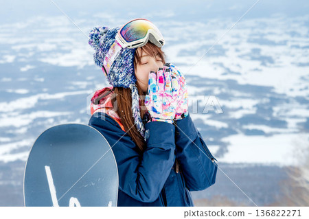 Young woman enjoying snowboarding at the top of the slope 136822271