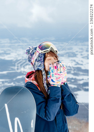 Young woman enjoying snowboarding at the top of the slope 136822274