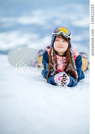Young woman enjoying snowboarding at the top of the slope 136822283