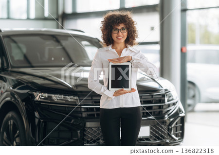 With digital tablet. Female employee is in the car retail shop With digital tablet. Female employee is in the car retail shop 136822318