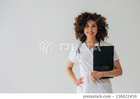 Black notepad is in hand. Beautiful doctor woman is in the studio Black notepad is in hand. Beautiful doctor woman is in the studio 136822450