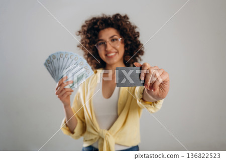 Lot of money and credit card in hands. Beautiful woman is in the studio Lot of money and credit card in hands. Beautiful woman is in the studio 136822523
