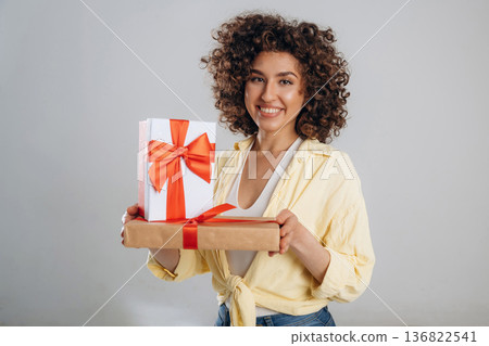 Present boxes are in hands. Beautiful woman is in the studio Present boxes are in hands. Beautiful woman is in the studio 136822541