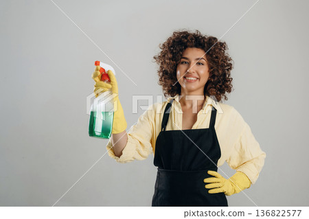 Household chemicals in hand, yellow gloves. Beautiful woman is in the studio 136822577