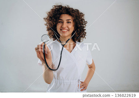 Listening through the stethoscope. Beautiful doctor woman is in the studio Listening through the stethoscope. Beautiful doctor woman is in the studio 136822619