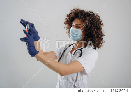 Vaccination concept. With syringe. Beautiful doctor woman is in the studio Vaccination concept. With syringe. Beautiful doctor woman is in the studio 136822654