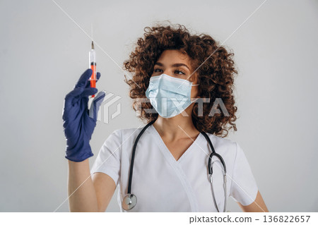 Vaccination concept. With syringe. Beautiful doctor woman is in the studio Vaccination concept. With syringe. Beautiful doctor woman is in the studio 136822657