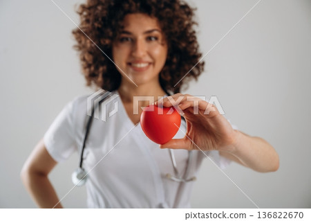 Cardiologist is with little heart toy. Beautiful doctor woman is in the studio Cardiologist is with little heart toy. Beautiful doctor woman is in the studio 136822670