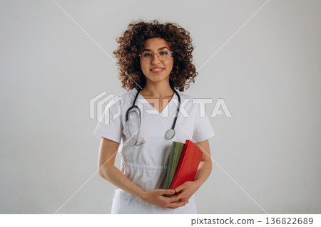 Educational material, notepads in hands. Beautiful student doctor woman is in the studio Educational material, notepads in hands. Beautiful student doctor woman is in the studio 136822689
