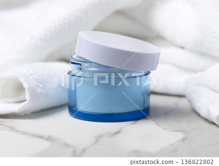 Opened blue cosmetic cream jar with a lid on stone near white bath towel, mockup 136822802