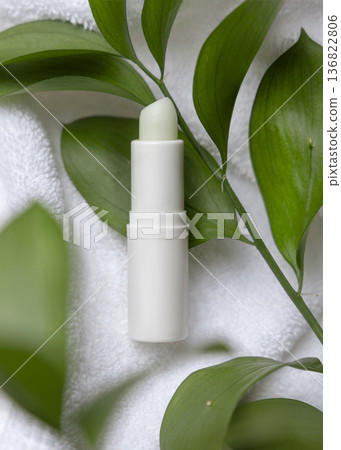 Mockup of blank opened lip balm stick on white bath towel and green leaves. Unbranded cosmetic Mockup of blank opened lip balm stick on white bath towel and green leaves. Unbranded cosmetic 136822806