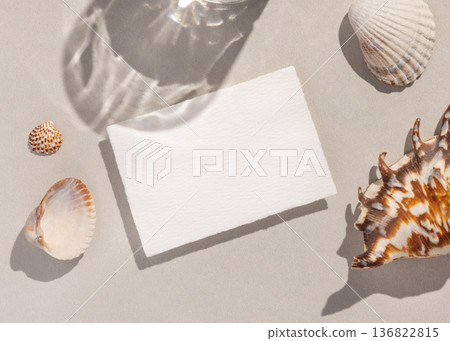Mockup of blank card on beige stone near seashells on stone, hard shadows, coastal wedding design Mockup of blank card on beige stone near seashells on stone, hard shadows, coastal wedding design 136822815
