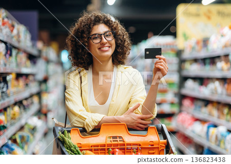 Credit or debit card in hand. Gorgeous woman is in the grocery store Credit or debit card in hand. Gorgeous woman is in the grocery store 136823438