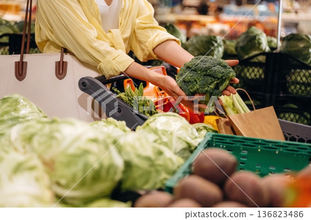 Holding cabbage. Close up view of woman that is choosing vegetables in the grocery store Holding cabbage. Close up view of woman that is choosing vegetables in the grocery store 136823486