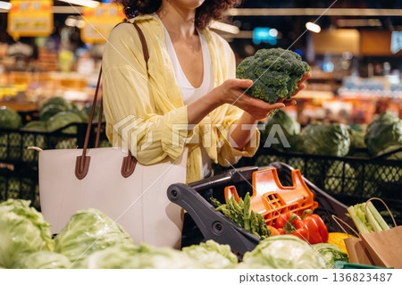 Holding cabbage. Close up view of woman that is choosing vegetables in the grocery store Holding cabbage. Close up view of woman that is choosing vegetables in the grocery store 136823487