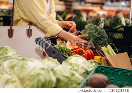 Holding cabbage. Close up view of woman that is choosing vegetables in the grocery store Holding cabbage. Close up view of woman that is choosing vegetables in the grocery store 136823488