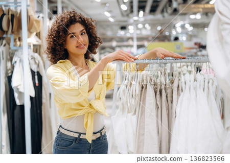 Wear is hanging. Woman is shopping in the clothing store 136823566