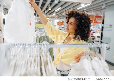 Wear is hanging. Woman is shopping in the clothing store 136823569