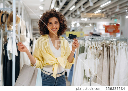 Ready to pay, holding credit card. Woman is shopping in the clothing store 136823584