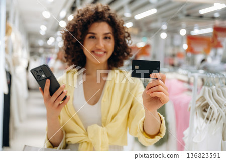 Payment by using credit card and phone. Woman is shopping in the clothing store Payment by using credit card and phone. Woman is shopping in the clothing store 136823591