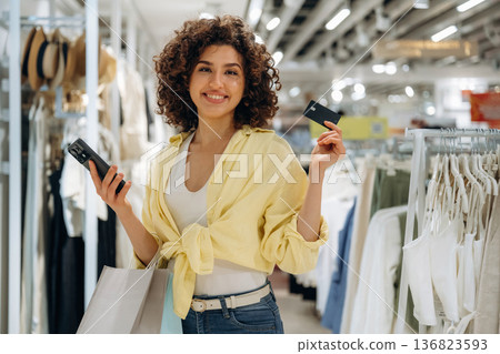 Payment by using credit card and phone. Woman is shopping in the clothing store Payment by using credit card and phone. Woman is shopping in the clothing store 136823593