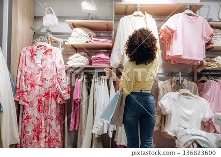 Rear view. Woman is shopping in the clothing store Rear view. Woman is shopping in the clothing store 136823600