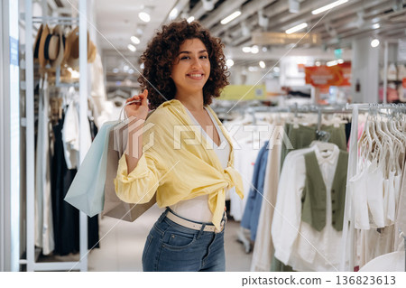 Finished the shopping, holding bags. Woman is in the clothing store Finished the shopping, holding bags. Woman is in the clothing store 136823613
