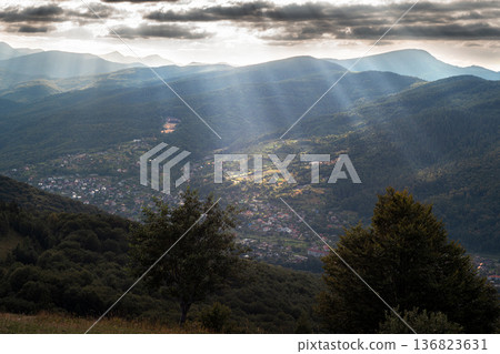 Mountain Valley with Sun Rays Breaking Through Clouds 136823631