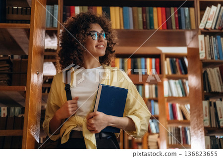 Holding the book. Beautiful woman is in the library Holding the book. Beautiful woman is in the library 136823655