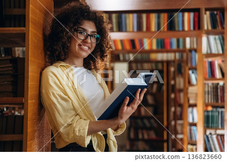 Leaning on the shelf. Beautiful woman is in the library Leaning on the shelf. Beautiful woman is in the library 136823660