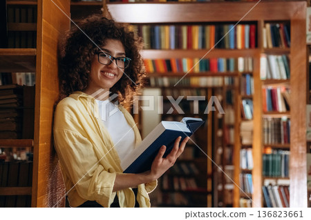 Leaning on the shelf. Beautiful woman is in the library 136823661