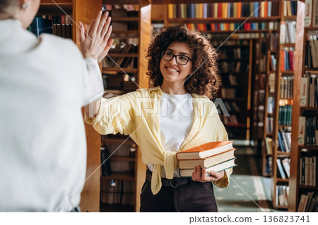 Two women are doing high five in the library 136823741