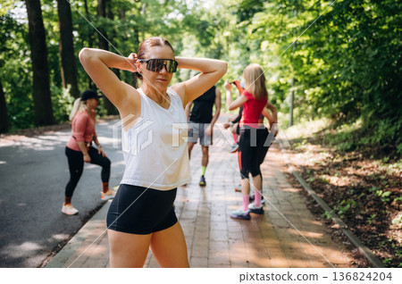 Person is standing. Group of runners are together outdoors Person is standing. Group of runners are together outdoors 136824204