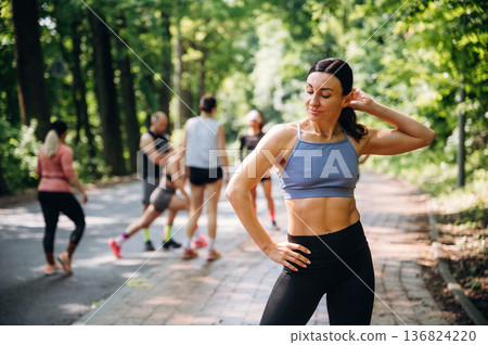 Blue top, black pants, standing. Group of runners are together outdoors Blue top, black pants, standing. Group of runners are together outdoors 136824220