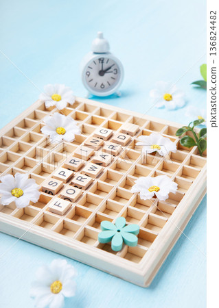 Daylight saving Time, Spring forward, Summer back concept. White Alarm Clock and Spring Daisy Flowers on Blue Background Daylight saving Time, Spring forward, Summer back concept. White Alarm Clock and Spring Daisy Flowers on Blue Background 136824482