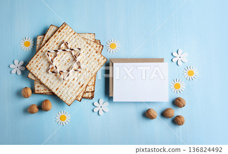 Passover holiday card with matzah, walnuts, yellow spring flowers on light blue background, gold and white accents, copy space 136824492