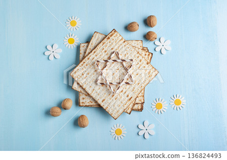 Passover holiday card with matzah, walnuts, yellow spring flowers on light blue background, top view, copy space 136824493
