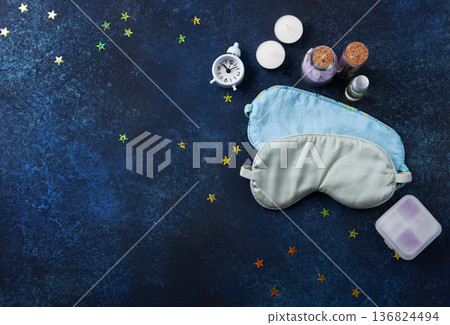 World Sleep Day concept. Bedtime accessories, sleep masks, and classic alarm clock on dark blue wooden background 136824494