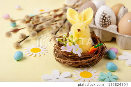 Easter spring  holiday card. Playful bunny, painted eggs, willow branches, paper flowers, decorative elements on yellow background 136824504