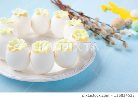 Easter spring holiday card. Playful bunny, painted eggs, willow branches, spring flowers, decorative elements on light blue background Easter spring holiday card. Playful bunny, painted eggs, willow branches, spring flowers, decorative elements on light blue background 136824522