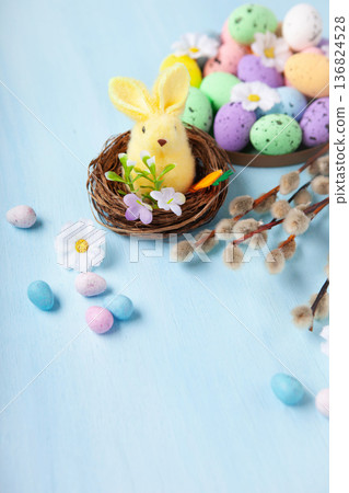 Easter spring holiday card. Playful bunny, painted eggs, willow branches, spring flowers, decorative elements on light blue background Easter spring holiday card. Playful bunny, painted eggs, willow branches, spring flowers, decorative elements on light blue background 136824528