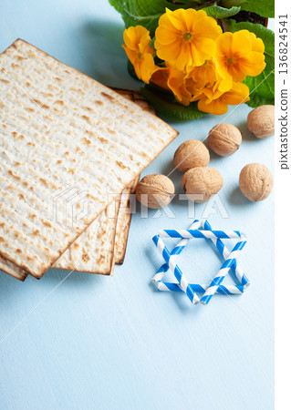 Passover holiday card with matzah, walnuts, yellow spring flowers on light blue background, gold and white accents, copy space 136824541