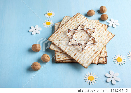 Passover holiday card with matzah, walnuts, yellow spring flowers on light blue background, gold and white accents, copy space 136824542